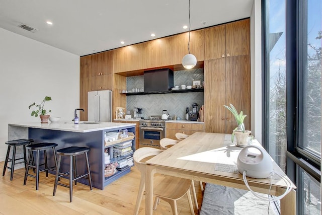 kitchen featuring high quality appliances, open shelves, a sink, light countertops, and a kitchen bar