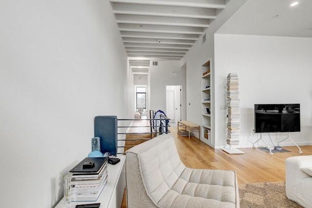 interior space featuring built in features, baseboards, wood finished floors, beamed ceiling, and visible vents
