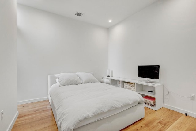 bedroom with baseboards, light wood finished floors, and visible vents