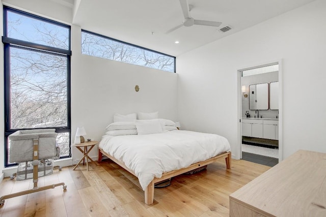 bedroom featuring visible vents, light wood-style floors, ceiling fan, and ensuite bath