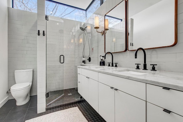 bathroom with double vanity, toilet, a sink, and a stall shower
