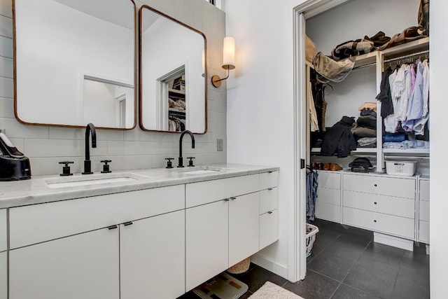 full bath with double vanity, a walk in closet, and a sink