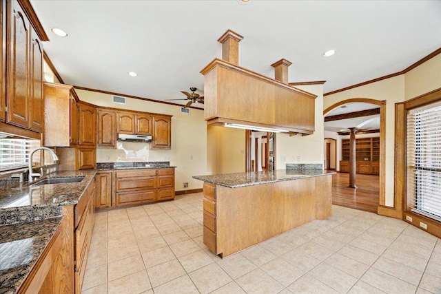 640 Woodlake Dr, Mcqueeney, TX 78123 - kitchen featuring decorative columns, ornamental molding, under cabinet range hood, ceiling fan, and dark stone countertops