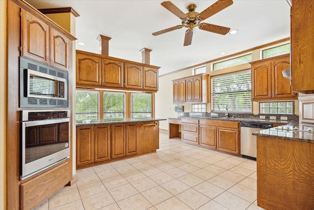 640 Woodlake Dr, Mcqueeney, TX 78123 - kitchen featuring appliances with stainless steel finishes, brown cabinetry, light tile patterned floors, and a healthy amount of sunlight