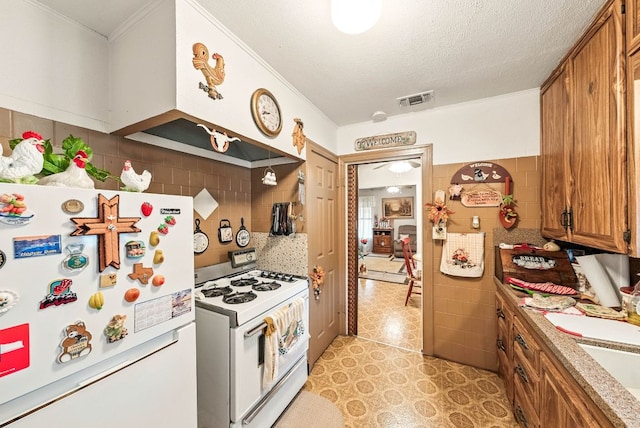 kitchen featuring visible vents, crown molding, white appliances, light countertops, and brown cabinets