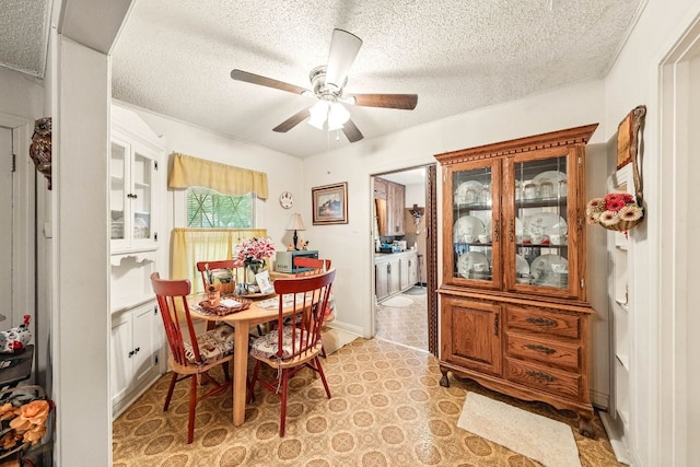 dining space with baseboards, a ceiling fan, and a textured ceiling