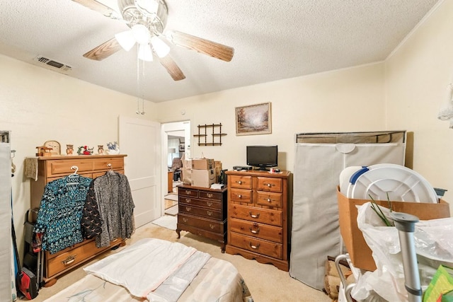 bedroom with visible vents, ornamental molding, light colored carpet, a textured ceiling, and a ceiling fan