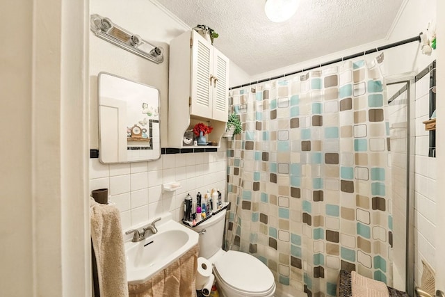 full bath featuring a sink, toilet, a textured ceiling, tile walls, and curtained shower