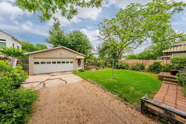 view of yard with a detached garage, fence, and an outdoor structure