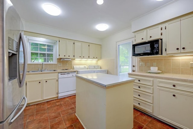 kitchen with white dishwasher, stainless steel fridge, a sink, black microwave, and washing machine and dryer