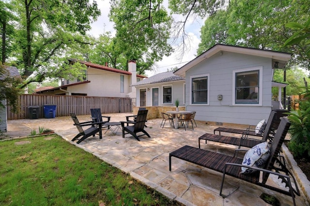 back of house with fence, a patio area, and a chimney