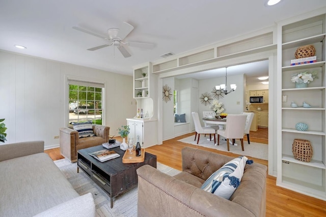living area with a chandelier, light wood finished floors, and a ceiling fan