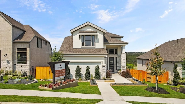 view of front facade with roof with shingles, fence, stucco siding, and a front lawn