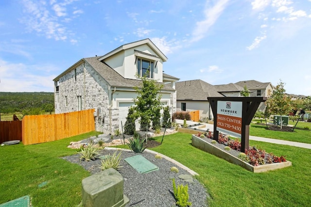 view of front of house featuring a front yard, a garage, fence, stone siding, and stucco siding