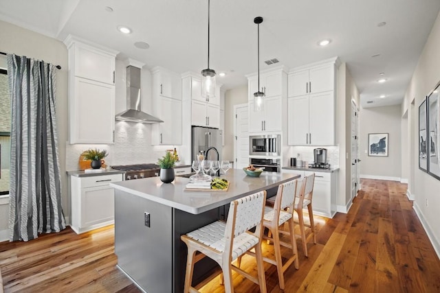 kitchen with white cabinets, appliances with stainless steel finishes, a breakfast bar area, decorative backsplash, and light wood-type flooring