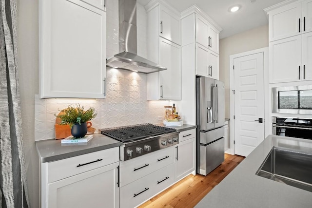 kitchen featuring decorative backsplash, a heating unit, recessed lighting, wall chimney exhaust hood, and appliances with stainless steel finishes