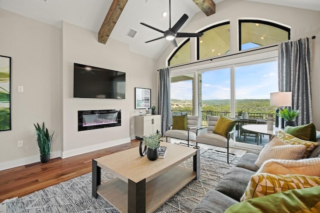 living room with visible vents, wood finished floors, beam ceiling, baseboards, and a glass covered fireplace