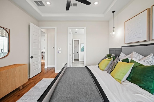 bedroom with visible vents, wood finished floors, and a raised ceiling