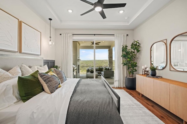 bedroom featuring recessed lighting, access to exterior, wood finished floors, and a raised ceiling