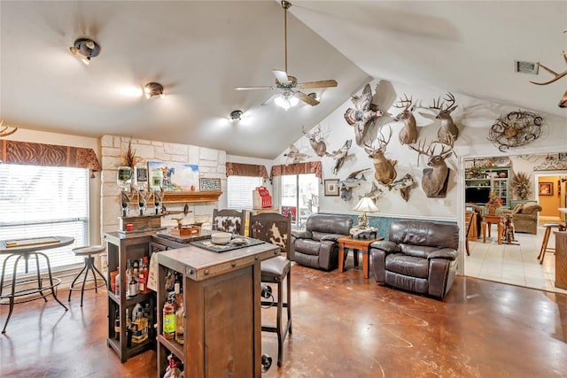 kitchen featuring ceiling fan, finished concrete flooring, a breakfast bar area, high vaulted ceiling, and visible vents