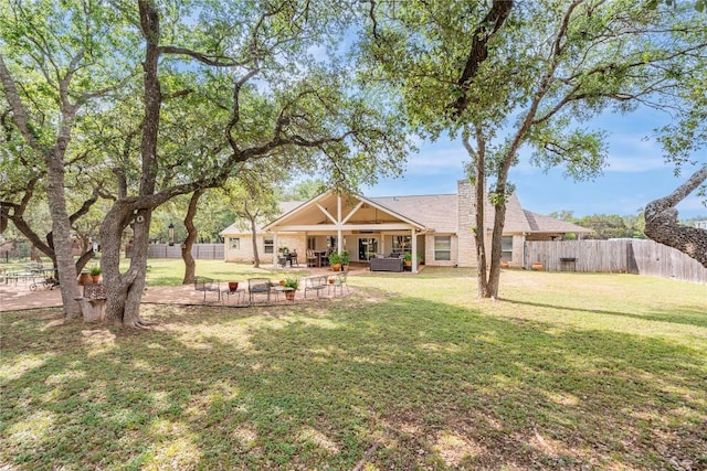 rear view of property featuring a fenced backyard, a patio area, a yard, and an outdoor hangout area