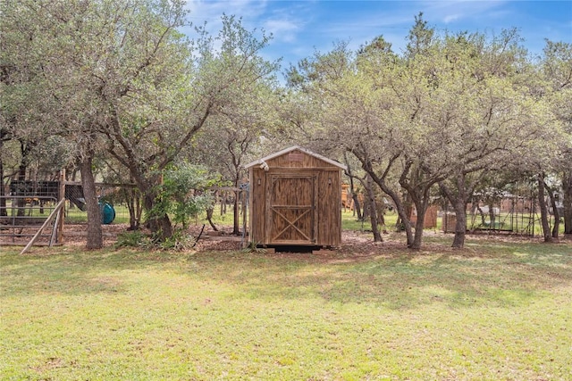 view of yard featuring a storage unit, fence, and an outbuilding