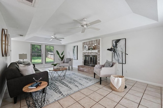 living room with ceiling fan, baseboards, light tile patterned floors, a tray ceiling, and visible vents