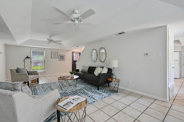 living room with light tile patterned flooring, ceiling fan, visible vents, and a raised ceiling