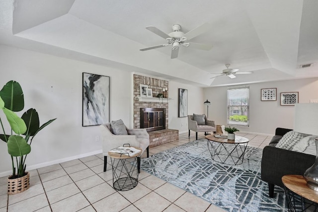 living area featuring visible vents, ceiling fan, light tile patterned floors, and a tray ceiling