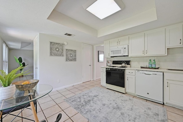 kitchen with visible vents, light tile patterned floors, a raised ceiling, white appliances, and white cabinetry