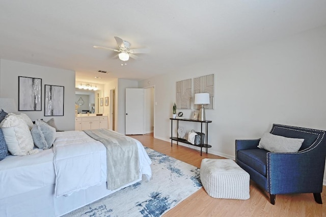 bedroom featuring visible vents, wood finished floors, baseboards, a ceiling fan, and ensuite bath