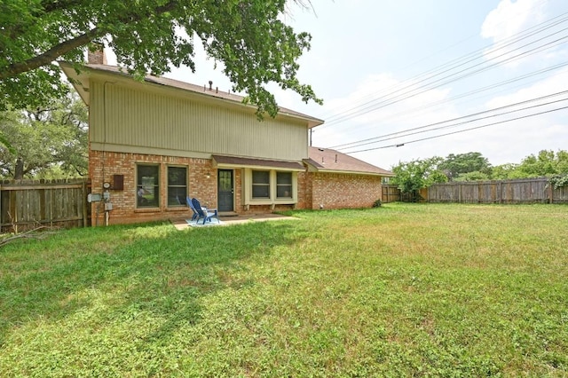 back of house with a yard, brick siding, a chimney, and a fenced backyard