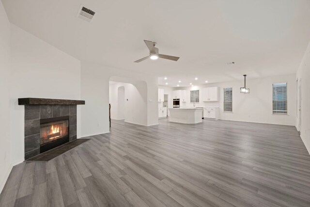 3944 Tufino Ln, Round Rock, TX 78665 - unfurnished living room with wood finished floors, a ceiling fan, a tiled fireplace, visible vents, and recessed lighting