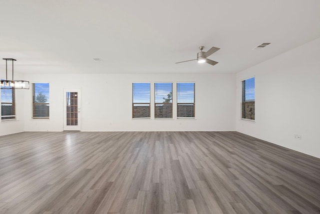 3944 Tufino Ln, Round Rock, TX 78665 - unfurnished room featuring visible vents, ceiling fan with notable chandelier, plenty of natural light, and wood finished floors