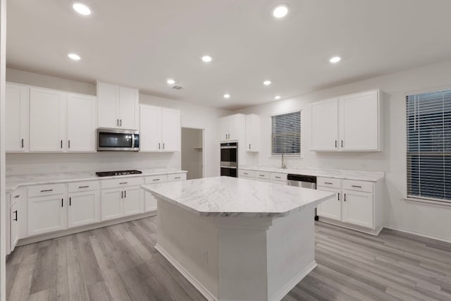 3944 Tufino Ln, Round Rock, TX 78665 - kitchen with light wood finished floors, stainless steel appliances, white cabinetry, and a kitchen island