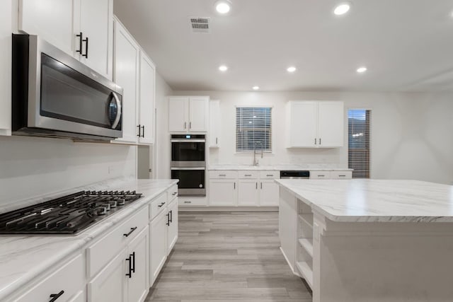 3944 Tufino Ln, Round Rock, TX 78665 - kitchen with white cabinets, appliances with stainless steel finishes, visible vents, and light wood finished floors