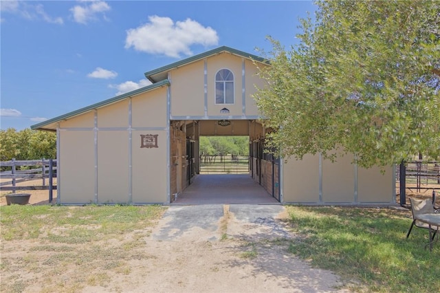 exterior space featuring dirt driveway, a carport, an exterior structure, an outdoor structure, and stucco siding