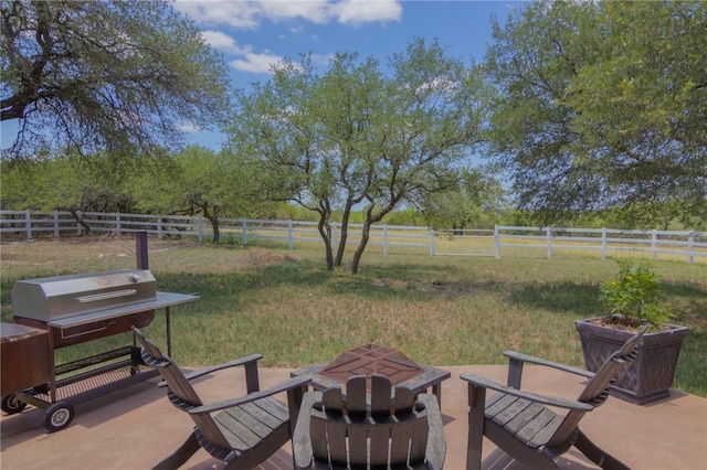view of yard featuring a rural view, a fenced backyard, and an outdoor fire pit