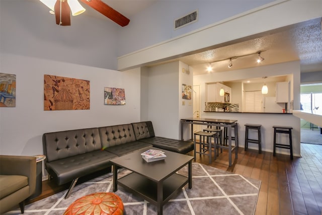 living area with visible vents, ceiling fan, and hardwood / wood-style flooring