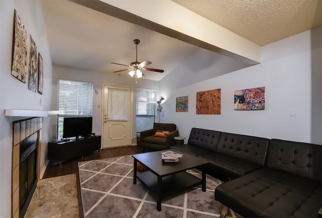 living area with a tiled fireplace, ceiling fan, wood finished floors, and lofted ceiling