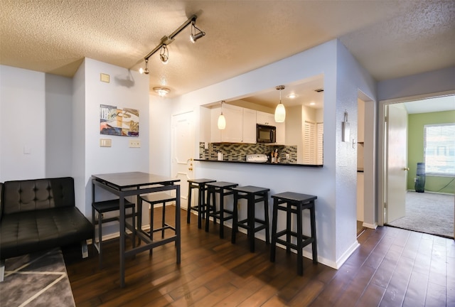 dining space with baseboards, a textured ceiling, and dark wood-style flooring