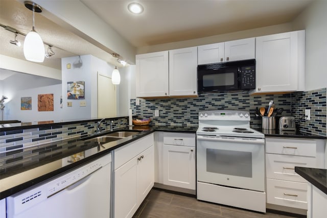 kitchen with a sink, dark countertops, white cabinets, and white appliances