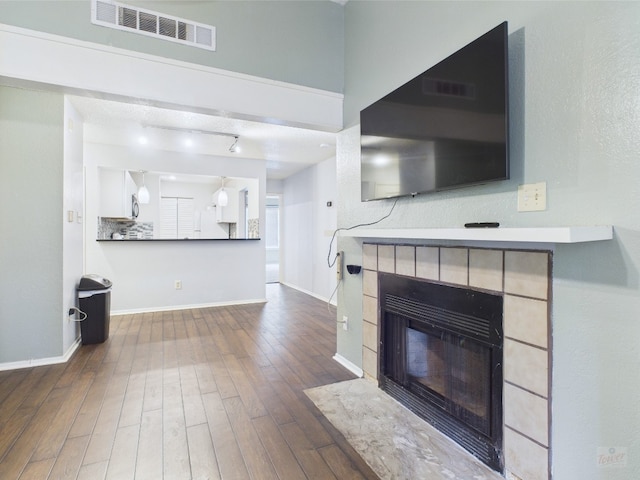 806 W 24th St Unit 312, Austin, TX 78705 - unfurnished living room featuring wood finished floors, baseboards, a tile fireplace, and track lighting