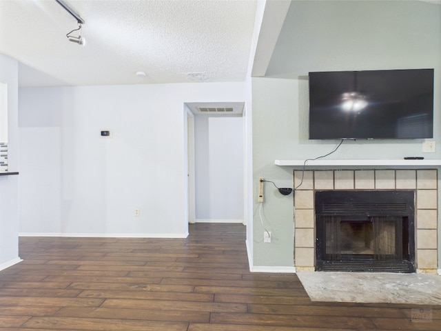 806 W 24th St Unit 312, Austin, TX 78705 - unfurnished living room featuring hardwood / wood-style floors, a tile fireplace, baseboards, a textured ceiling, and rail lighting