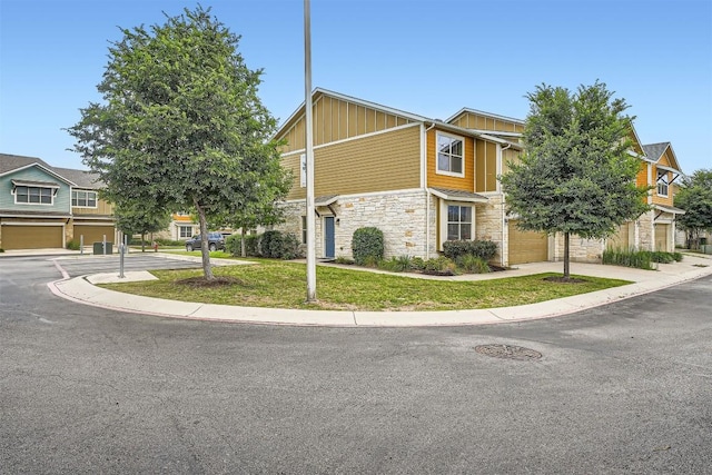 516 E Slaughter Ln Unit 1101, Austin, TX 78744 - view of front facade featuring board and batten siding, a front lawn, concrete driveway, an attached garage, and stone siding