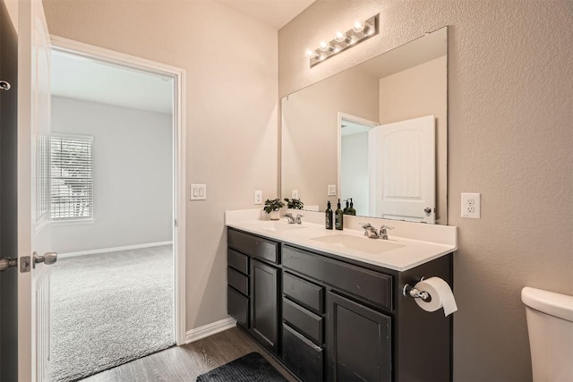516 E Slaughter Ln Unit 1101, Austin, TX 78744 - bathroom featuring double vanity, a sink, wood finished floors, and toilet