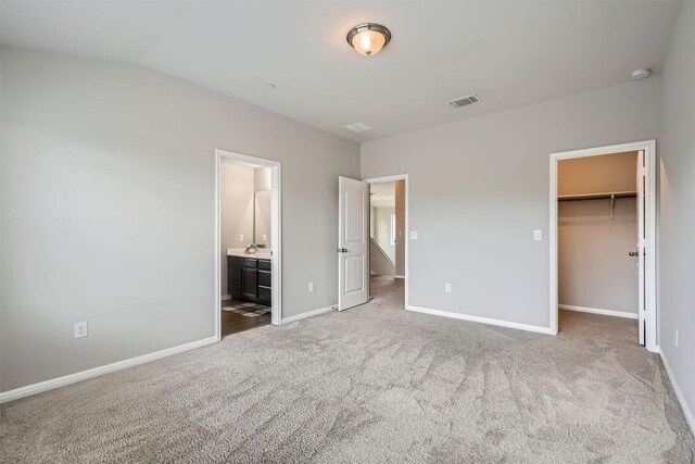 516 E Slaughter Ln Unit 1101, Austin, TX 78744 - unfurnished bedroom with a walk in closet, ensuite bath, carpet floors, baseboards, and visible vents