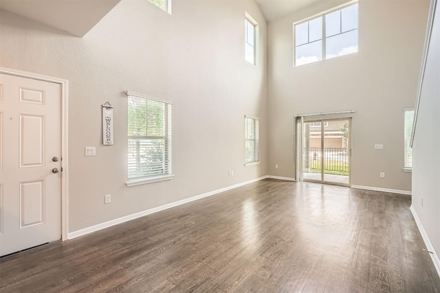 516 E Slaughter Ln Unit 1101, Austin, TX 78744 - unfurnished living room with baseboards, plenty of natural light, dark wood-type flooring, and a towering ceiling