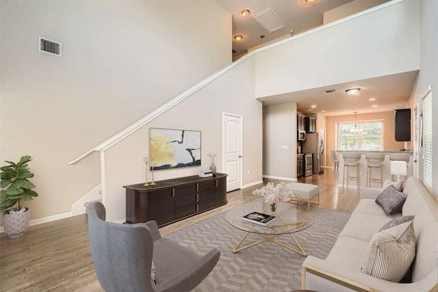 516 E Slaughter Ln Unit 1101, Austin, TX 78744 - living room with visible vents, stairs, baseboards, a high ceiling, and light wood finished floors