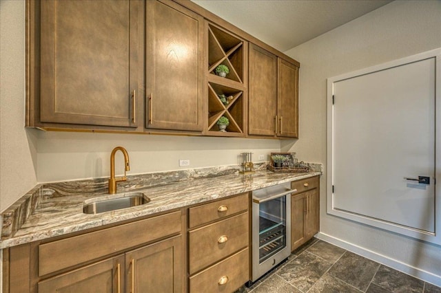 kitchen featuring open shelves, a sink, light stone counters, baseboards, and beverage cooler